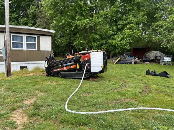 Ditch Witch directional boring rig pulling electric under a yard at a campground