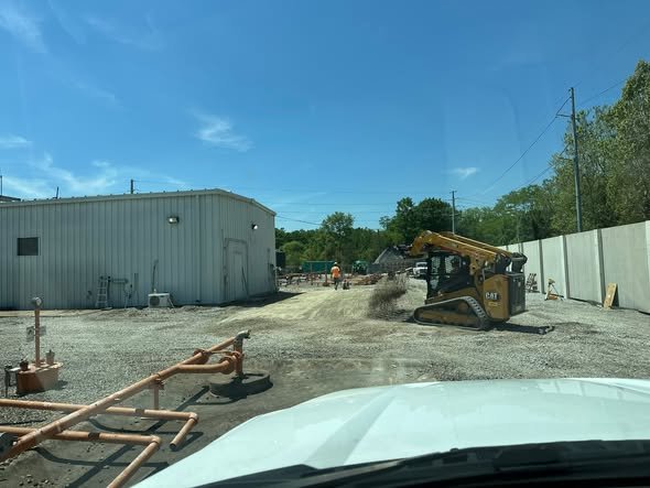 CAT skid steer grading a gravel lot beside a metal building